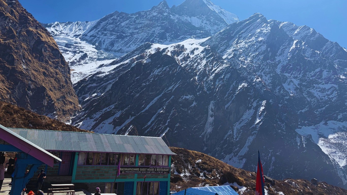Teahouse with outdoor chairs at Machhapuchhre Base Camp (MBC), with a clear view of Fishtail Mountain (Machhapuchhre) in the background.