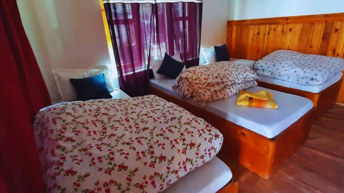 Neatly made comfortable bed with warm blankets and pillows in a teahouse room, ideal for trekkers resting during the trail.