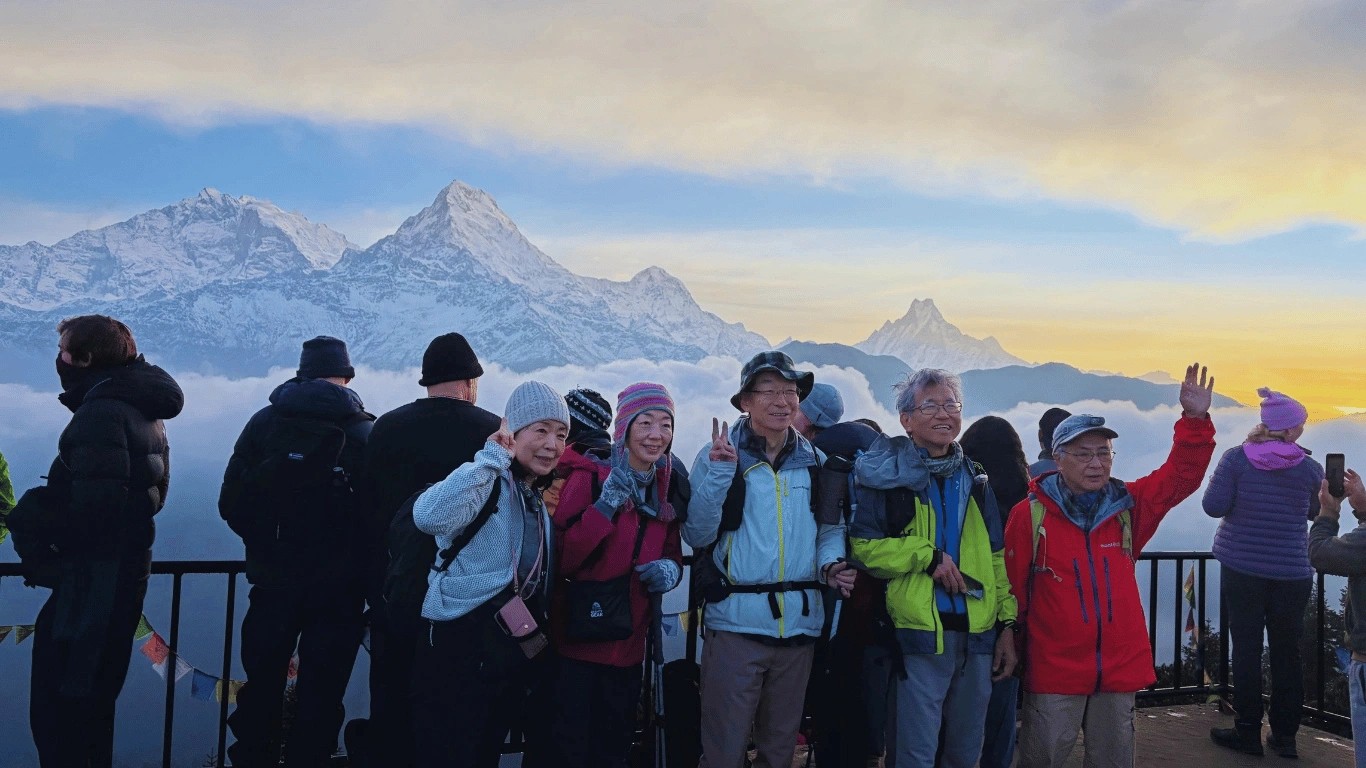 Group of happy older trekkers at Poon Hill enjoying panoramic Himalayan mountain views.