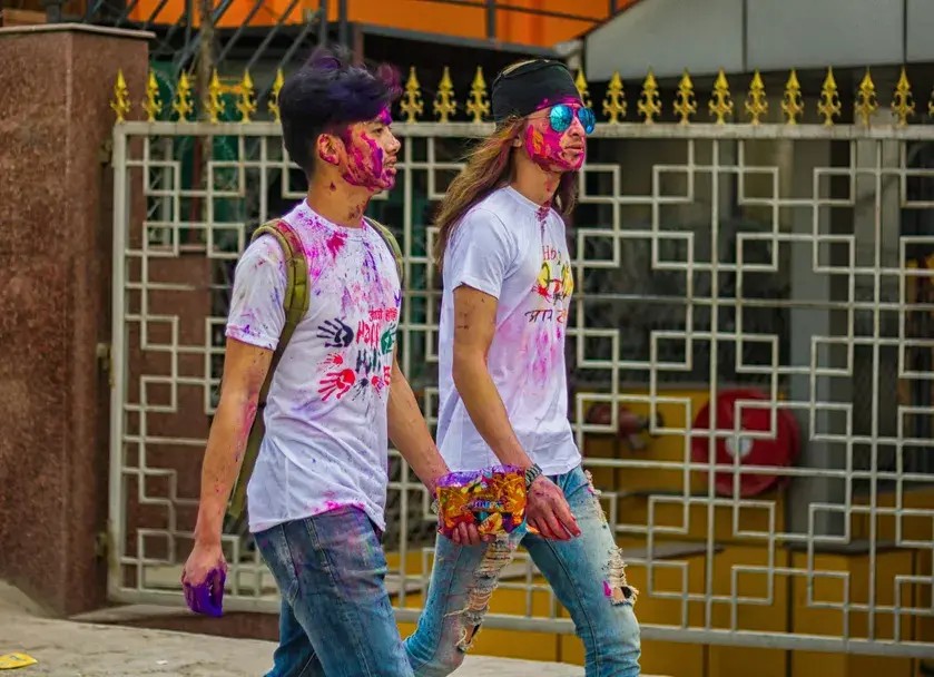 A person walking through a cloud of vibrant Holi colors.