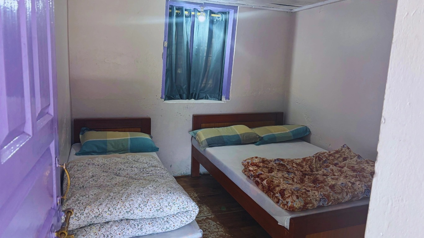 Simple teahouse room with one large bed and one small bed in Deurali along the Annapurna Base Camp Trek.