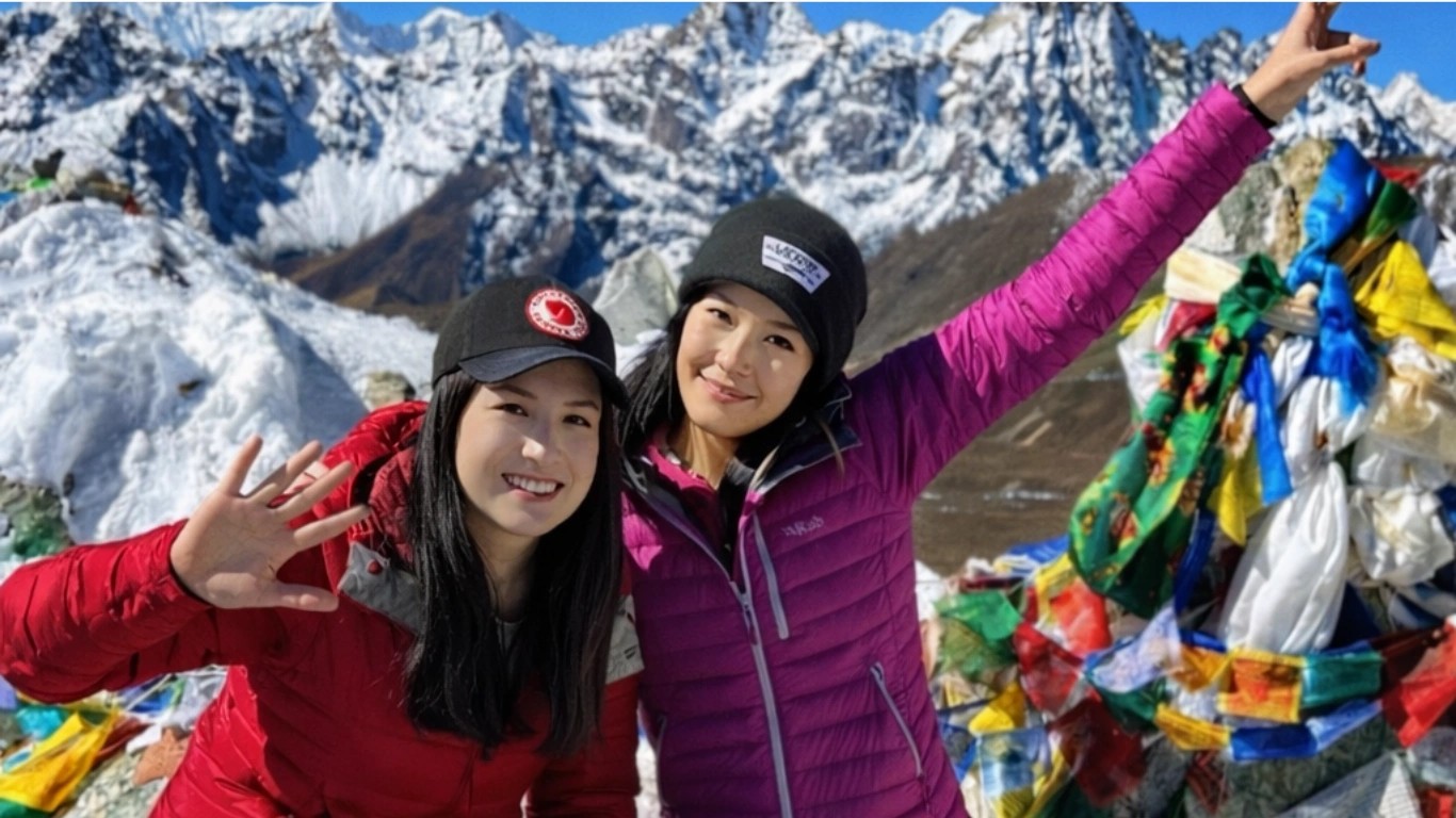 Two female trekkers posing at a high mountain pass during the Everest Three Passes Trek in Nepal's Khumbu region.