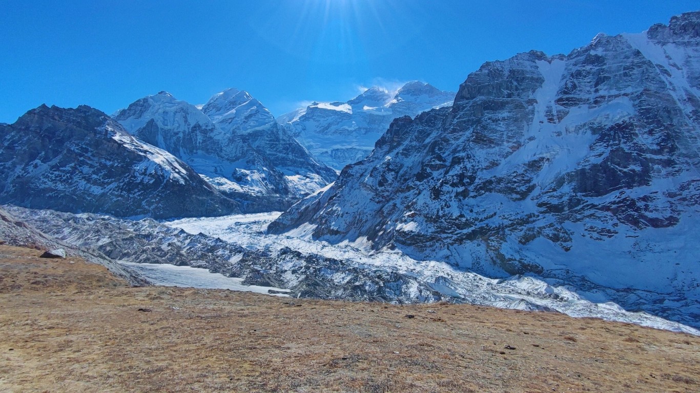 Trekkers walking along the Kanchenjunga trails with majestic mountain ranges in the background.