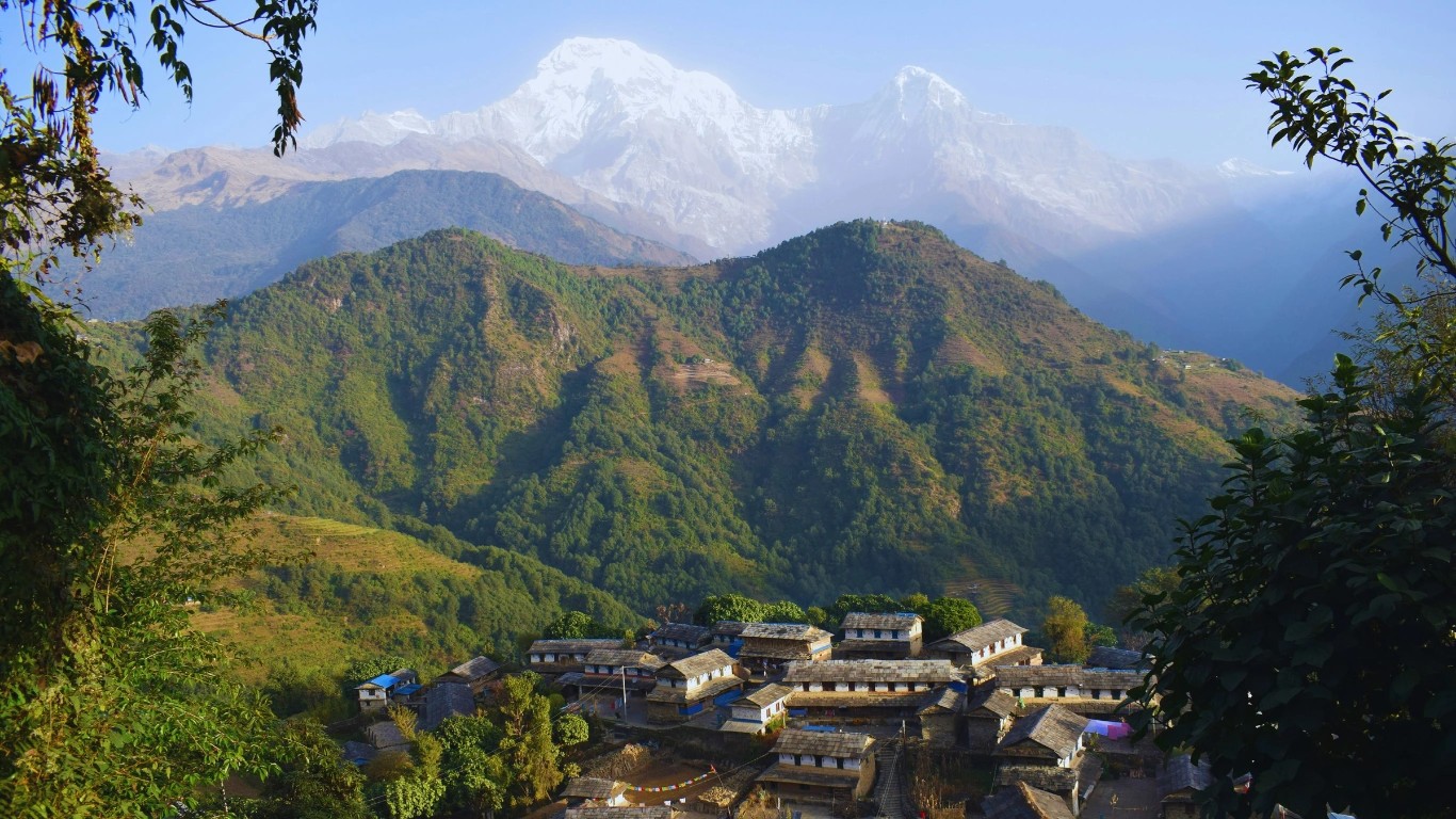 Trekking in Nepal in Ghandruk village, featuring traditional Gurung houses and Annapurna I glowing at sunset.