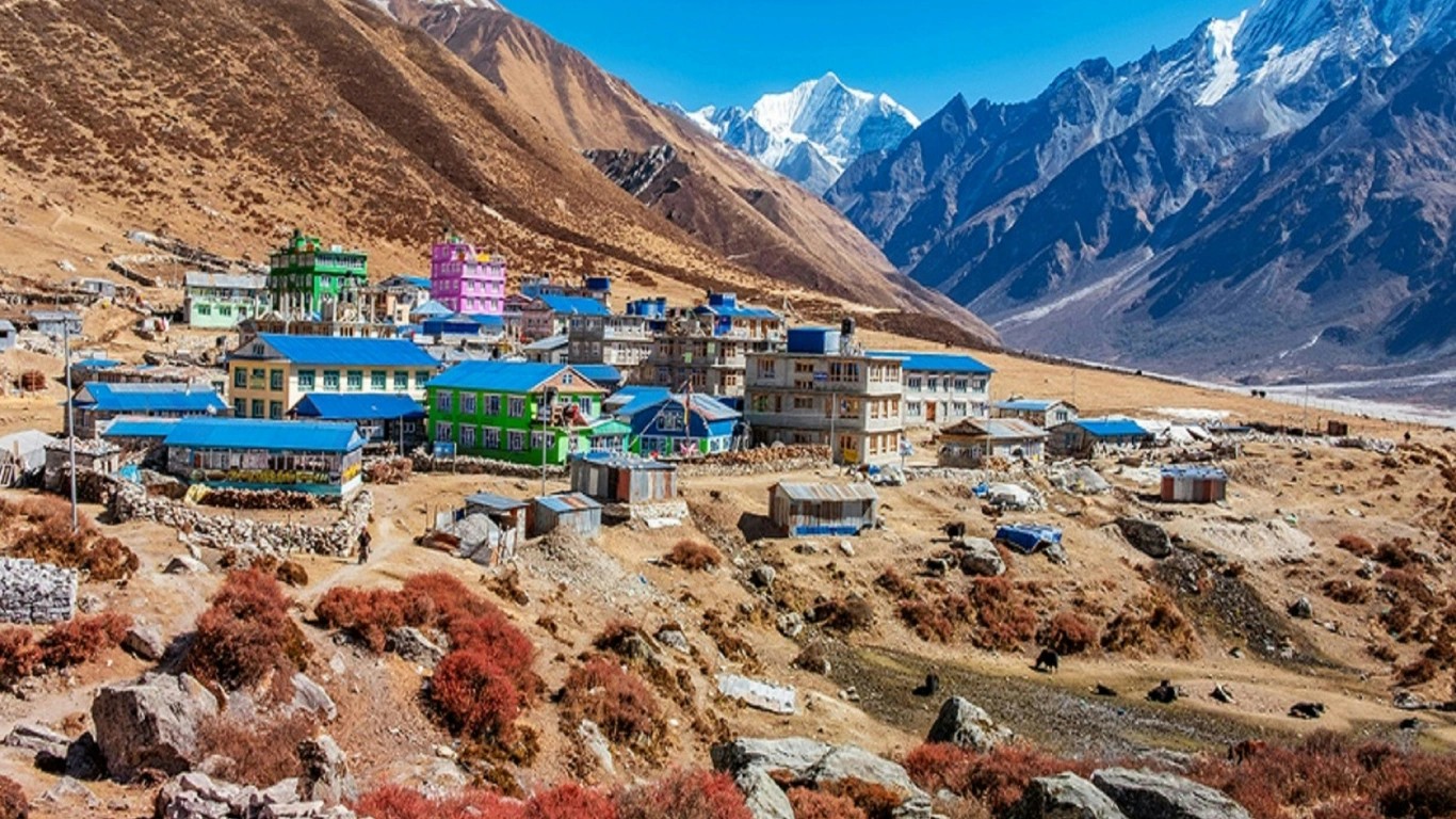 Kyanjin Gompa in Langtang Valley under bright sunshine with snow-capped mountains and clear blue sky during the Langtang Valley Trek.