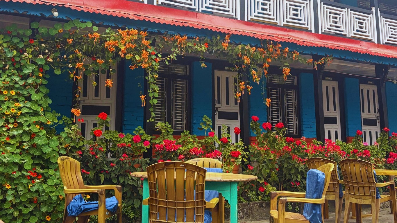 Teahouse exterior in Jhinu Danda with outdoor chairs and colorful flowers hanging outside the room.