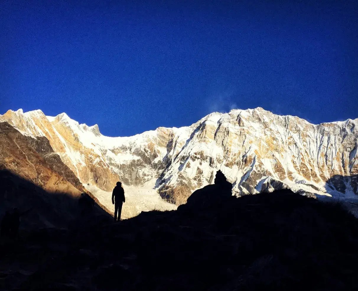 Group of trekkers standing with folded hands in front of Annapurna I peak during the Annapurna Base Camp spiritual trek in Nepal.