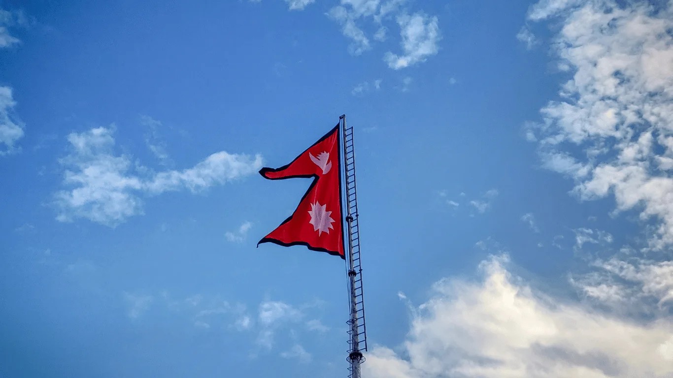 National flag of Nepal with two crimson triangular pennants, blue borders, and white moon and sun symbols.