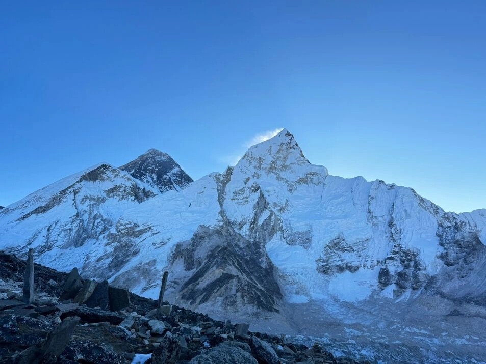 Panoramic mountain view of Mount Everest under a bright white sun in the late afternoon sky, just before sunset in the Everest region of Nepal.