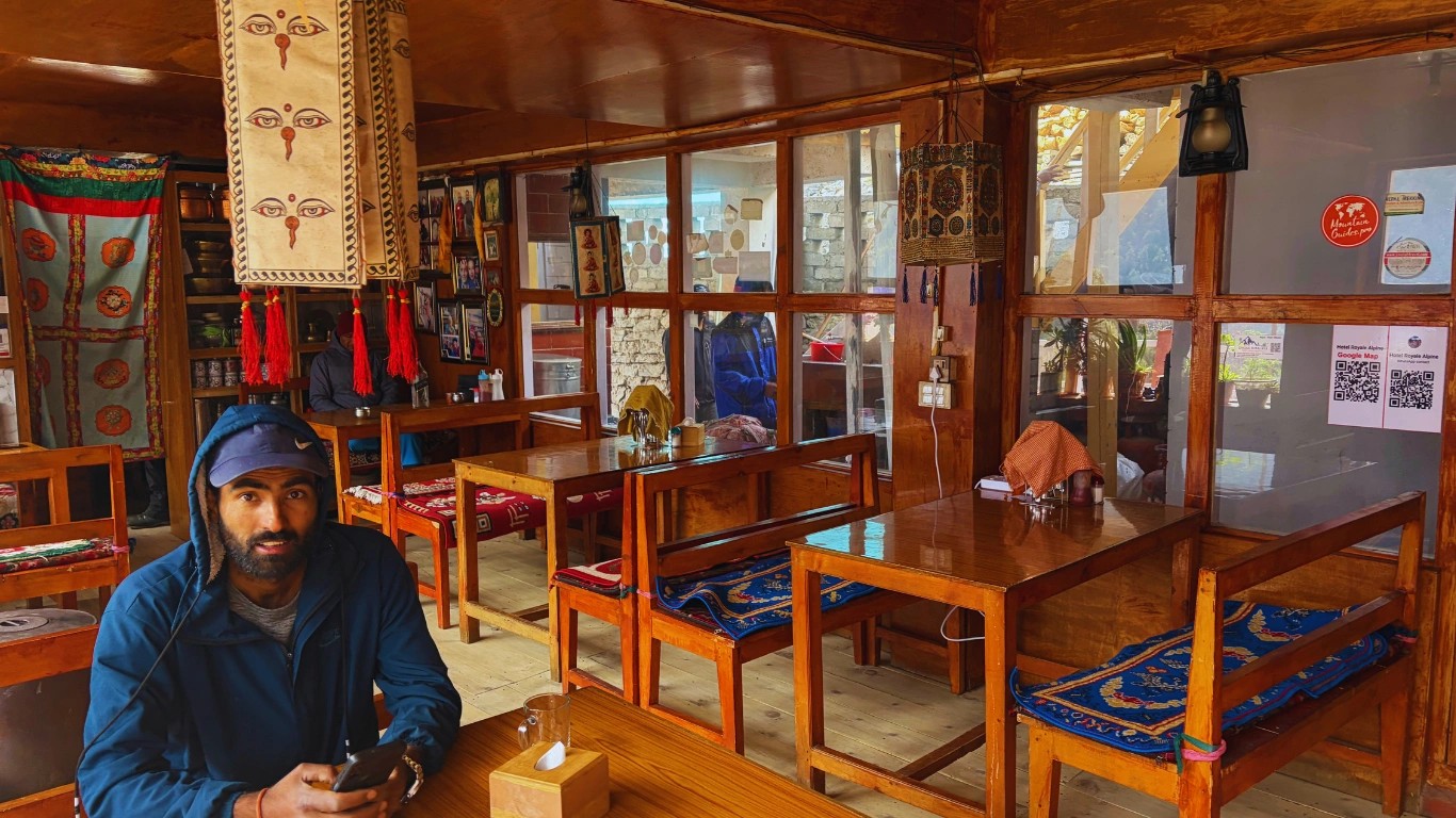 A clean dining hall at Hotel Mandala, Upper Pisang, featuring a Majestic Trails Nepal guide sitting and a charging port for trekkers.
