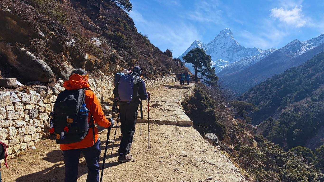 Trekkers hiking Everest Base Camp trail inside Sagarmatha National Park with Ama Dablam peak Nepal