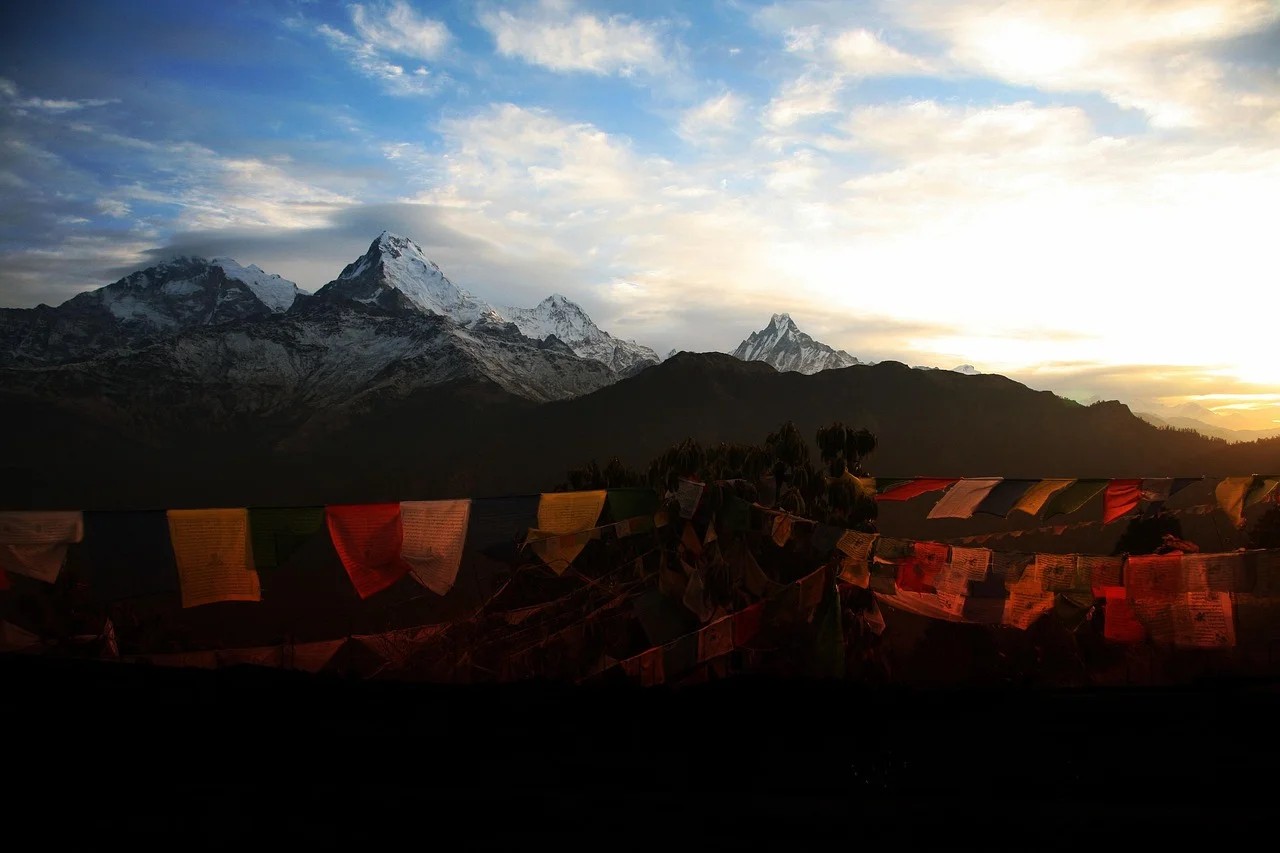 Prayer flags in the foreground at Poon Hill viewpoint with the Annapurna mountain range visible in the background before sunrise.