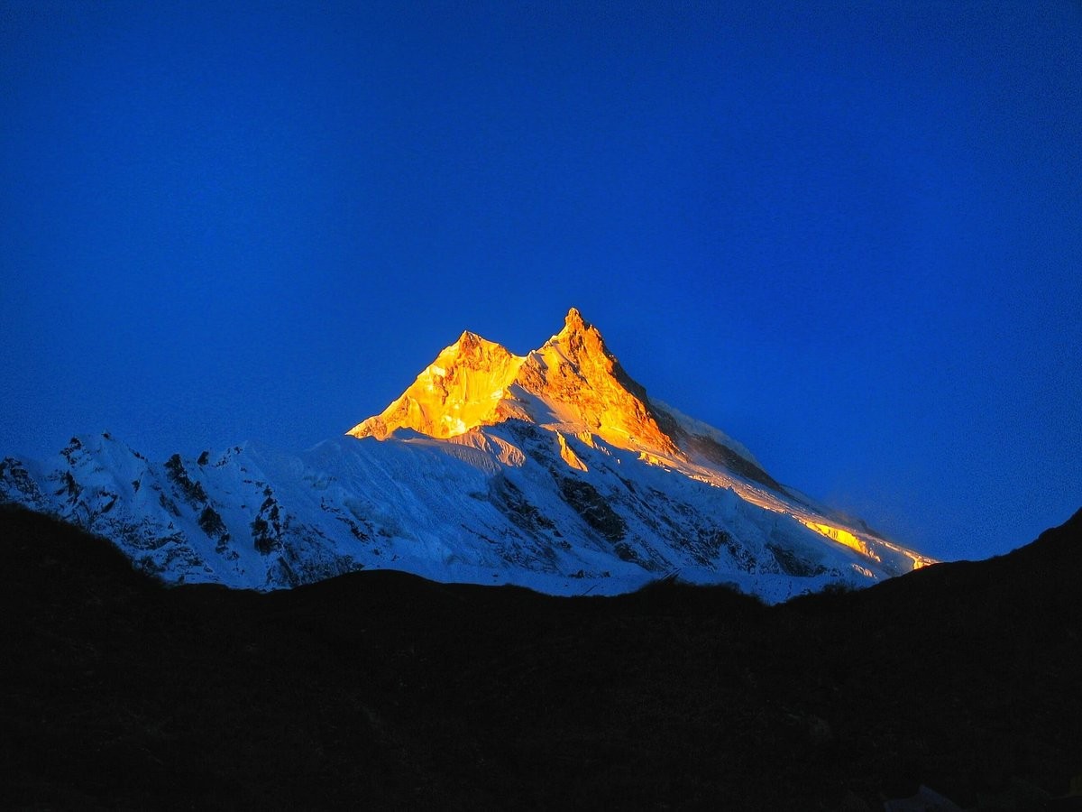 Trekking in Nepal with sunrise casting golden light on Mount Manaslu and surrounding Himalayan landscapes.