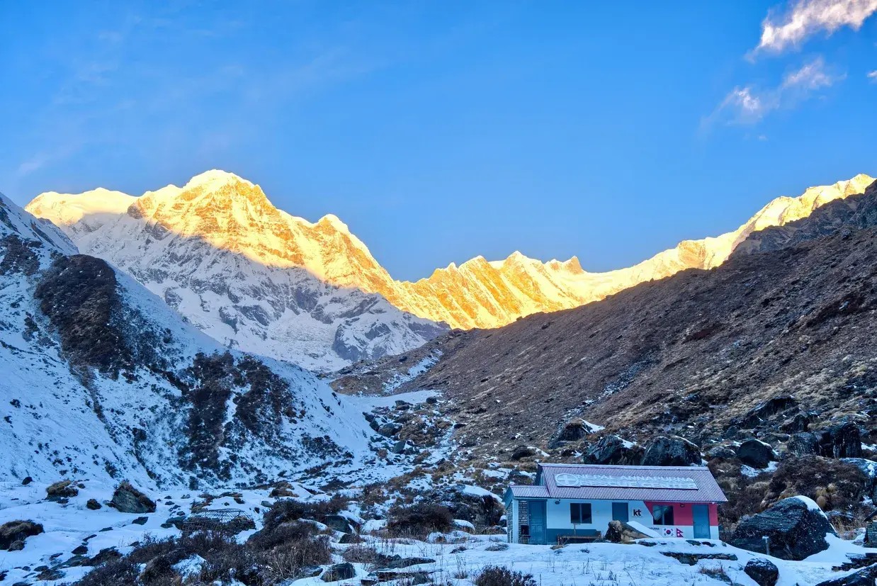 Trekkers standing at Annapurna Base Camp in December with snow-covered landscape and clear Himalayan peaks, showcasing trekking in Nepal in December.