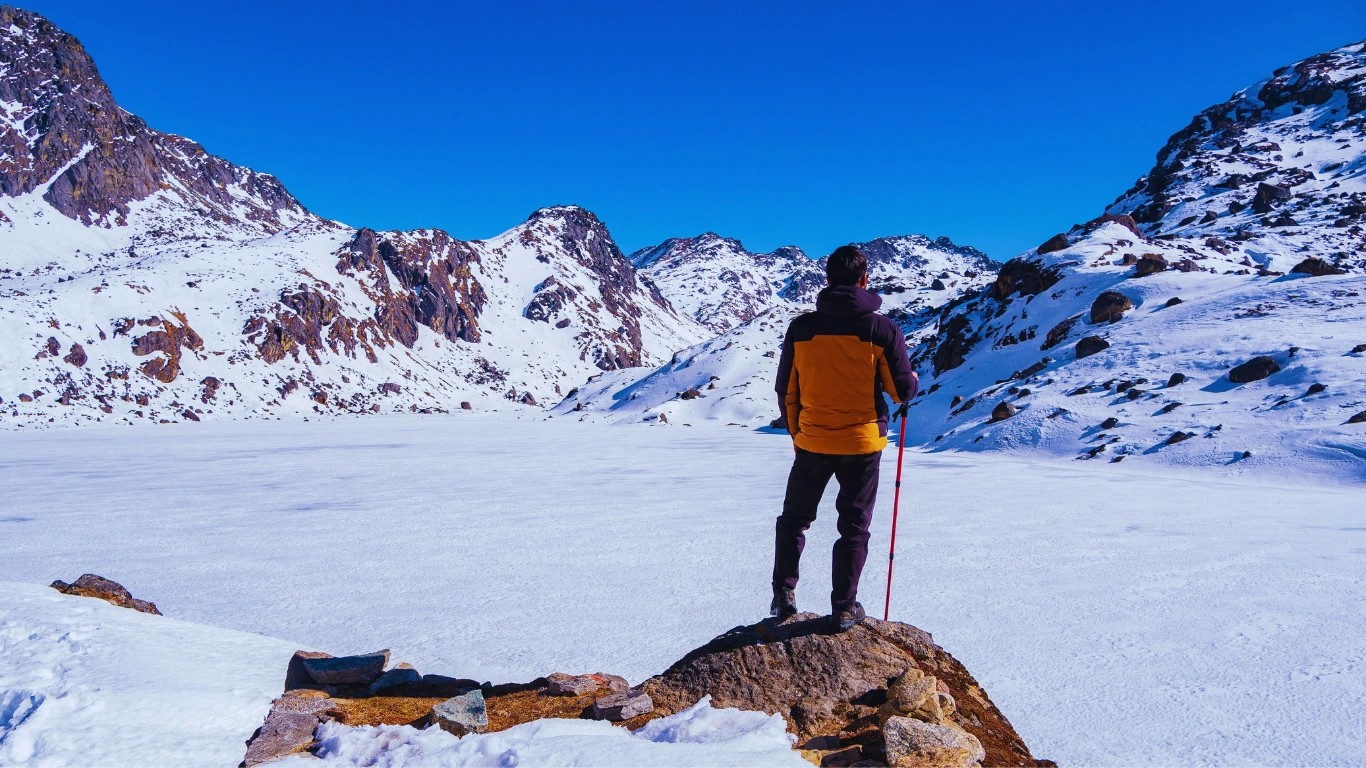 trekkers watching the frozen gosaikunda lake during the winter
