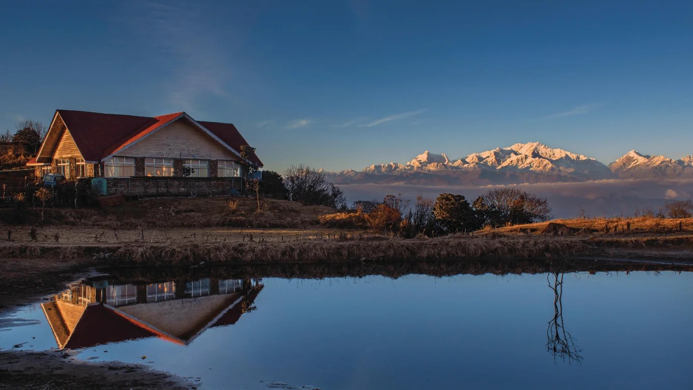Panoramic view of Mount Kanchenjunga’s towering snow-covered peaks above forested Himalayan ridges, illustrating the mountain’s immense height and scale from Darjeeling.