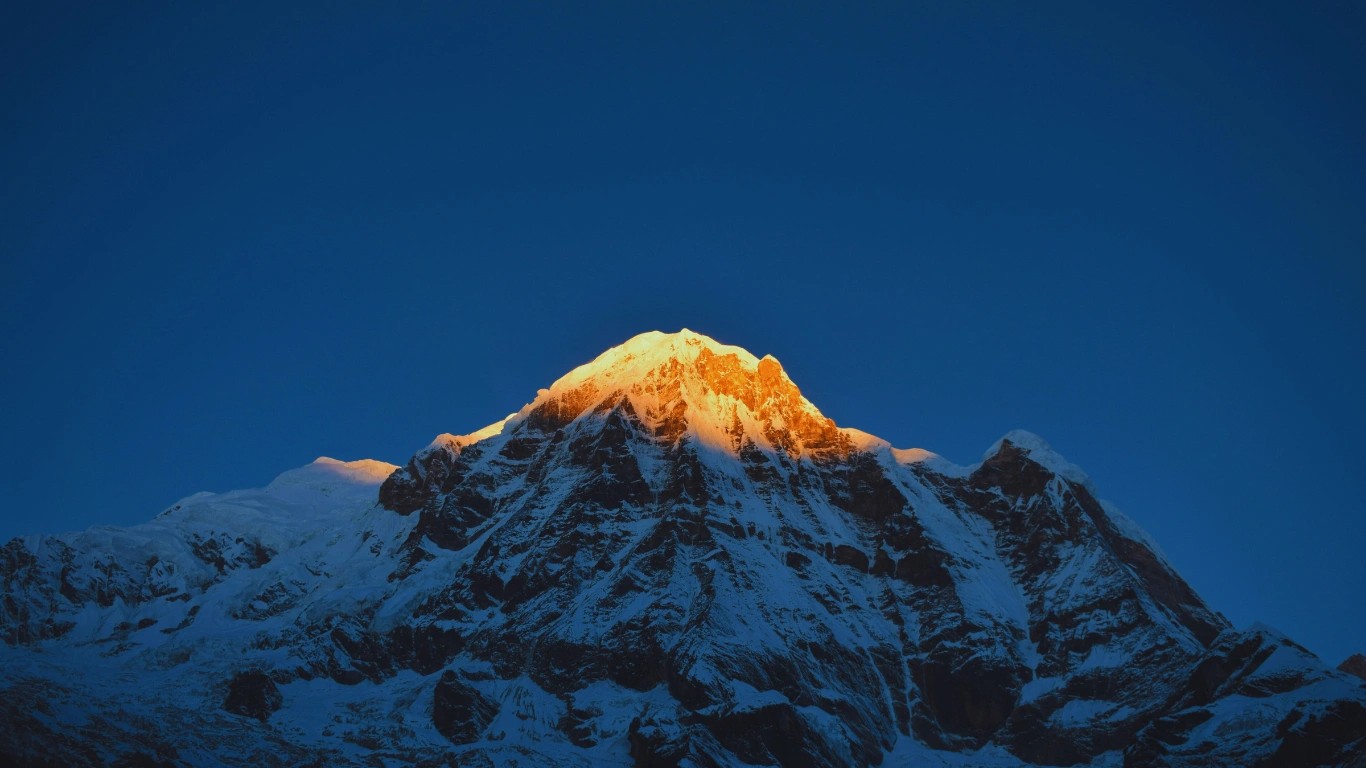 Summit of Annapurna South glowing in golden light above Annapurna Base Camp.