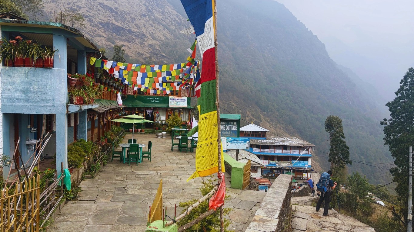 Teahouse lodges in Chhomrong with outdoor chairs and colorful prayer flags along the Annapurna Base Camp Trek.