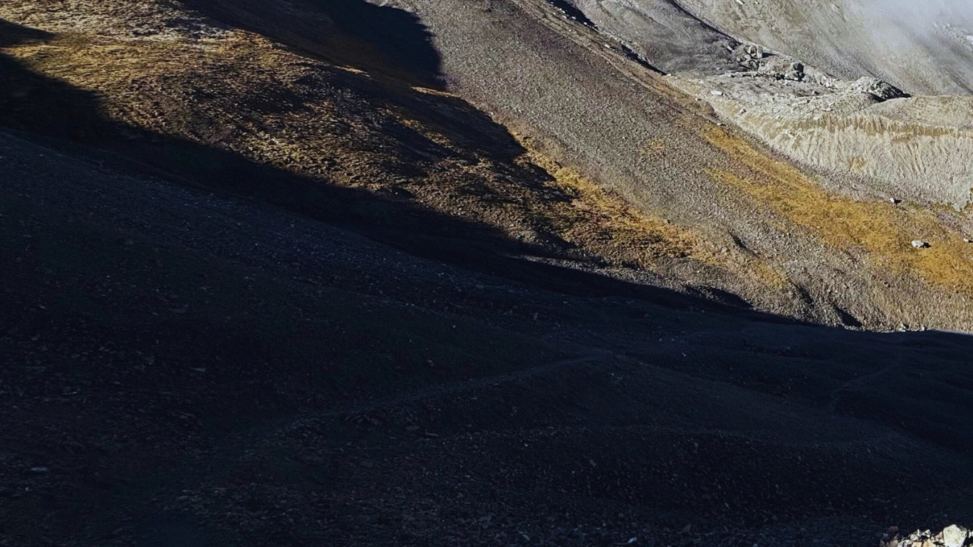 Rocky descent trail from Thorong La Pass toward Muktinath Temple with dramatic views of Mustang valley and barren brown mountains below