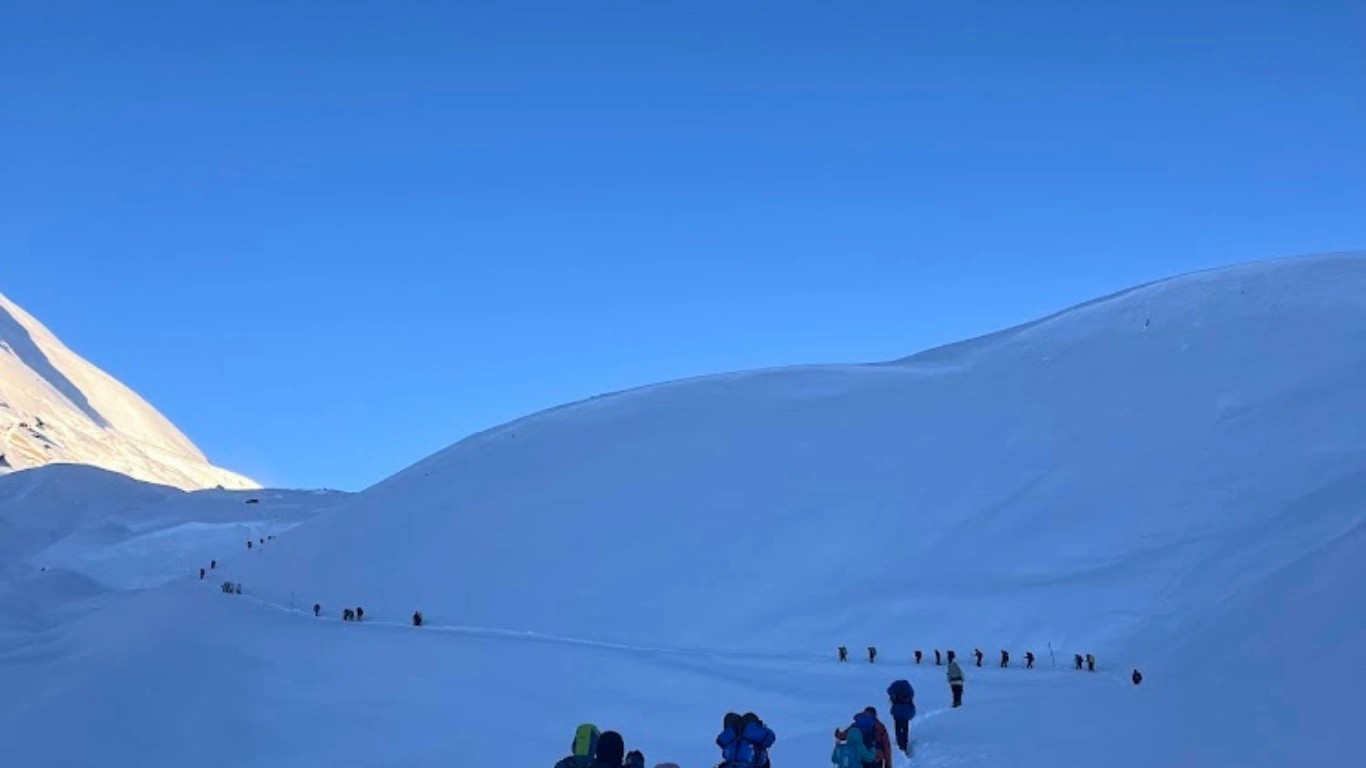 trekkers heading to thorang la pass in snow path
