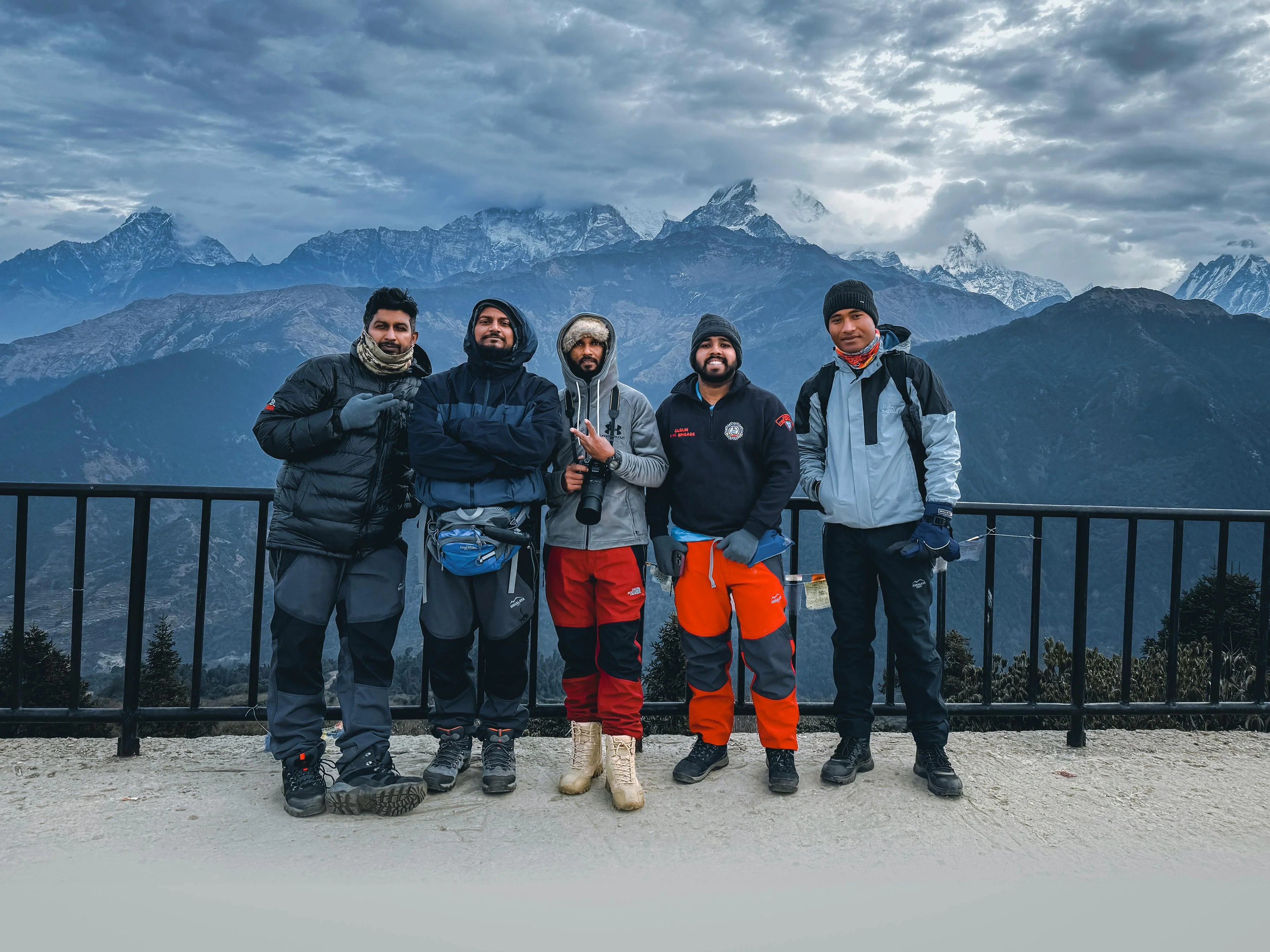 Trekkers at Poon Hill viewpoint during monsoon season with Annapurna mountains emerging through dramatic clouds in Nepal