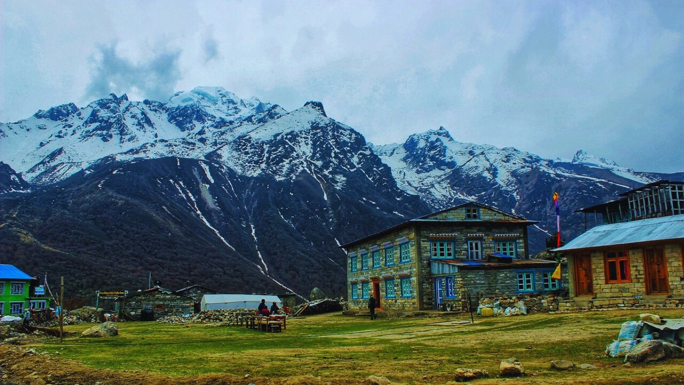 Langtang Valley during monsoon season with lush green landscape, waterfalls and trekkers on trail in Nepal Himalayas