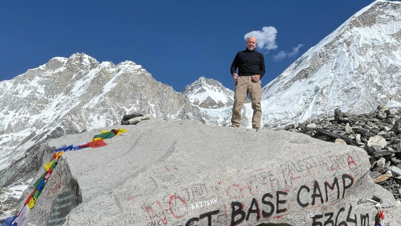 70-year-old trekker posing at the Everest Base Camp sign in Nepal during the Everest Base Camp Trek.