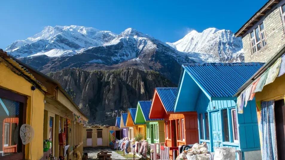 Traditional colorful teahouses in Manang with Gangapurna Mountain rising behind along the Apple Pie Trek route in Nepal.