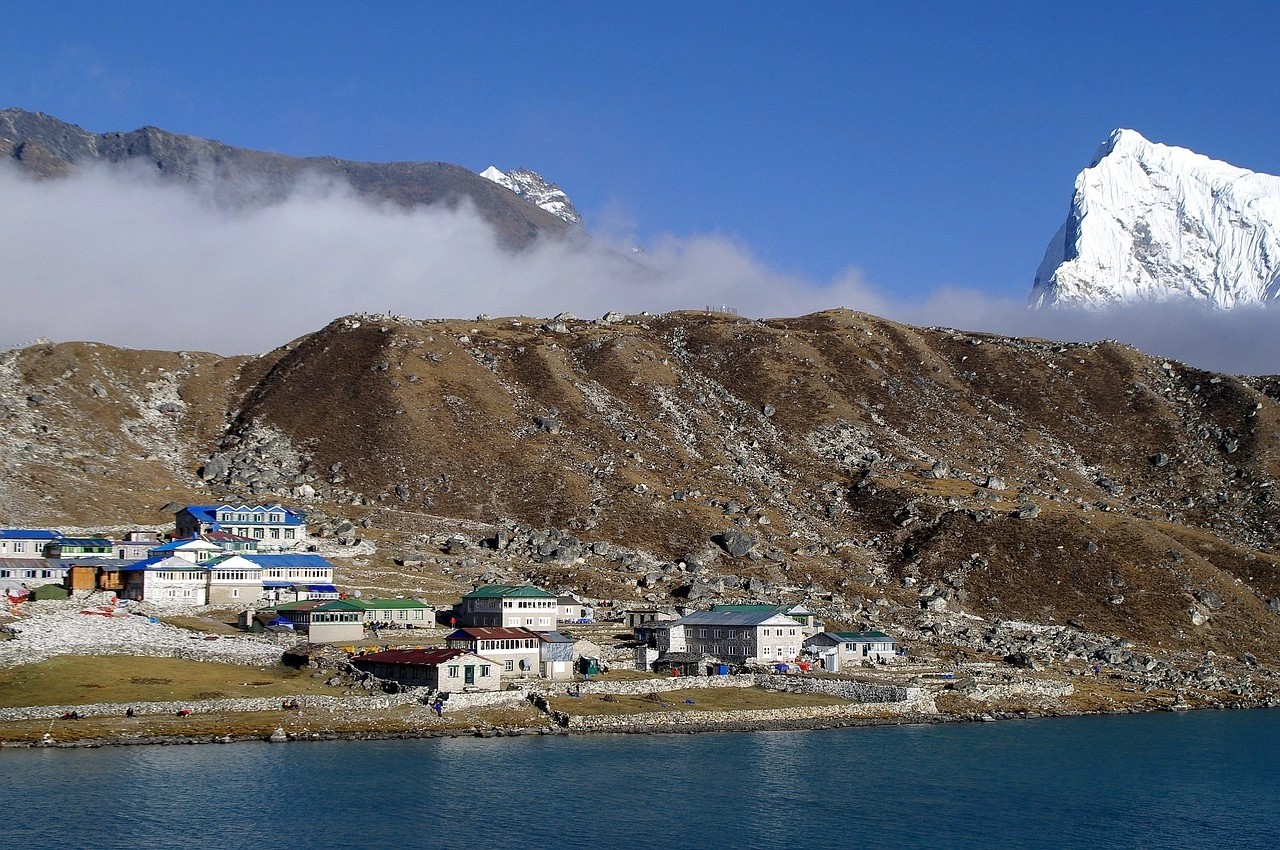 Turquoise Gokyo Lake surrounded by Himalayan peaks and traditional teahouses during the Gokyo Lakes Trek in Nepal.