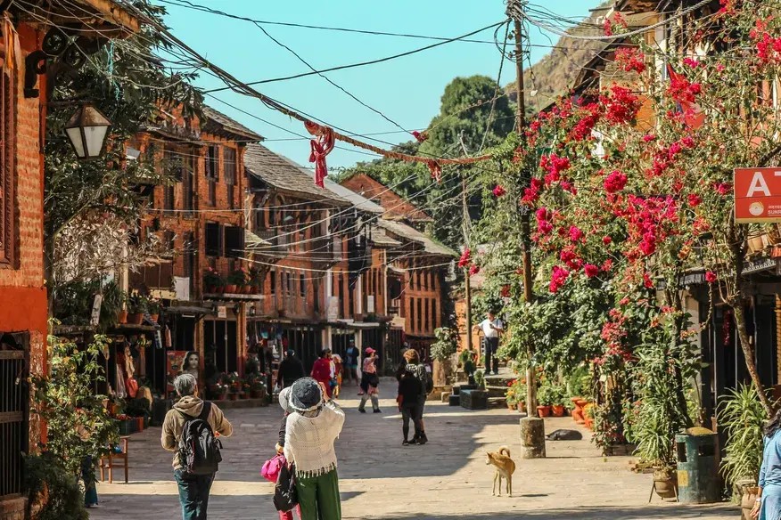 Couple walking on a quiet street in Bandipur Nepal with traditional houses and shops lining the road.