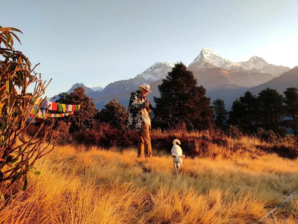 Solo trekker taking photos of the Annapurna mountain range from Poon Hill viewpoint during the Ghorepani Poon Hill Trek.