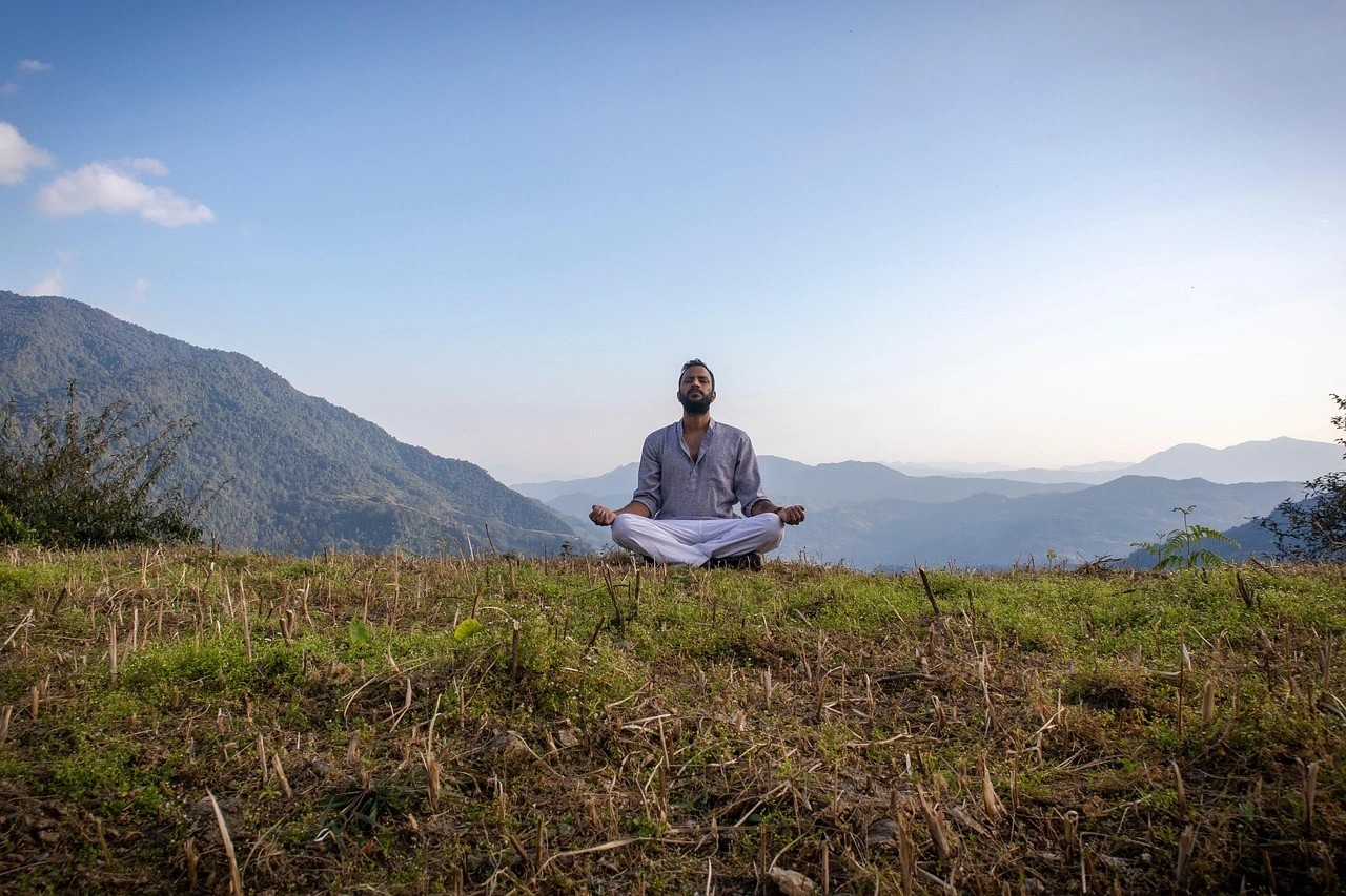 Traveler practicing meditation in Dhampus village on a wellness tour to Nepal, with panoramic Himalayan views, emphasizing mindfulness, relaxation, and wellness experiences.
