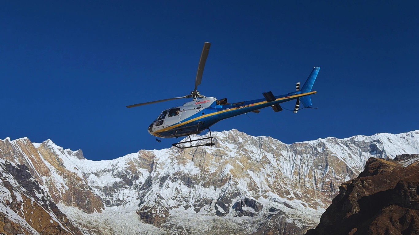 Helicopter flying in front of Annapurna I showing the exact Annapurna 1 location in the Annapurna region of Nepal with towering snow-covered Himalayan peaks in the background.