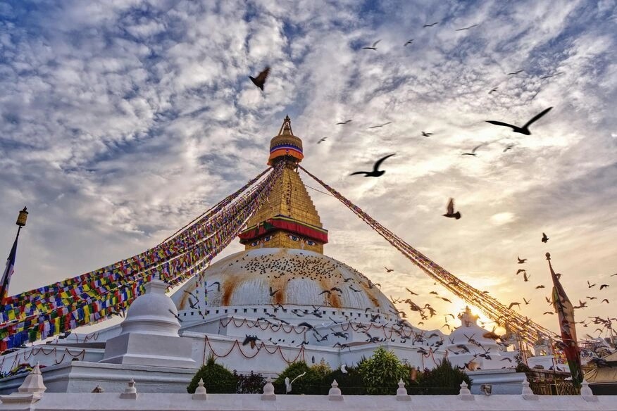Boudhanath Stupa in Kathmandu, Nepal, with prayer flags and pilgrims circling the monument.