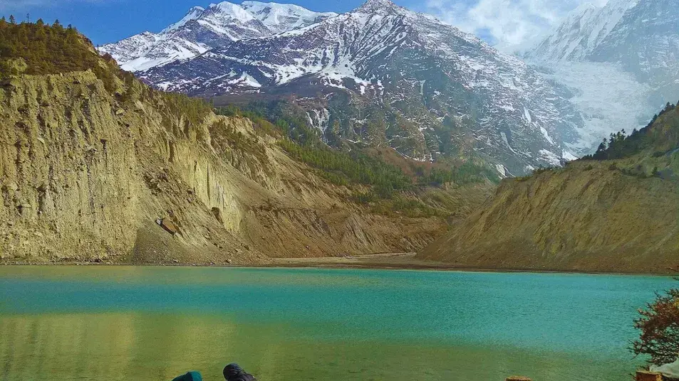 Trekker standing in front of Gangapurna Lake with Gangapurna Peak in the background, Annapurna region, Nepal lake trek.