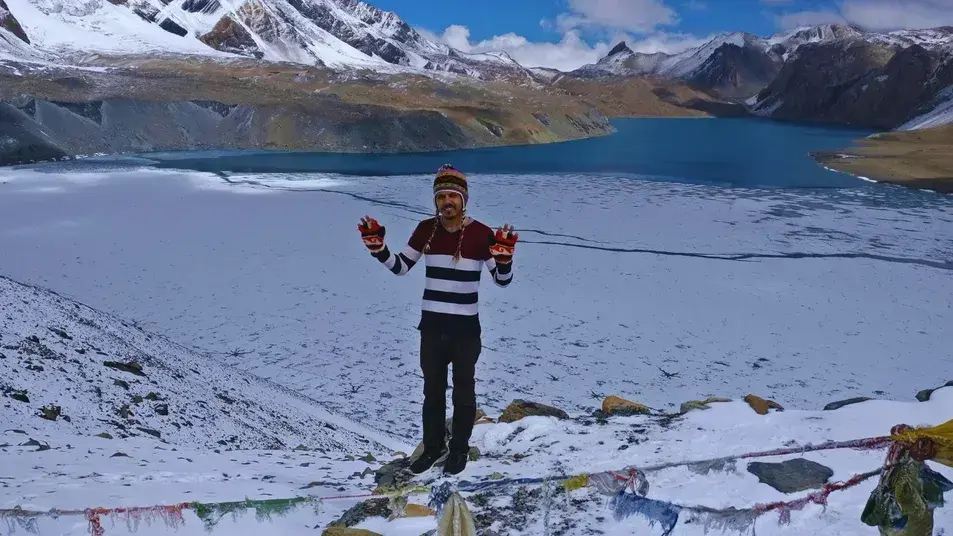 Group of trekkers standing in front of Tilicho Lake with snow-capped Himalayan peaks reflecting in the turquoise water during Nepal Lake Trek.
