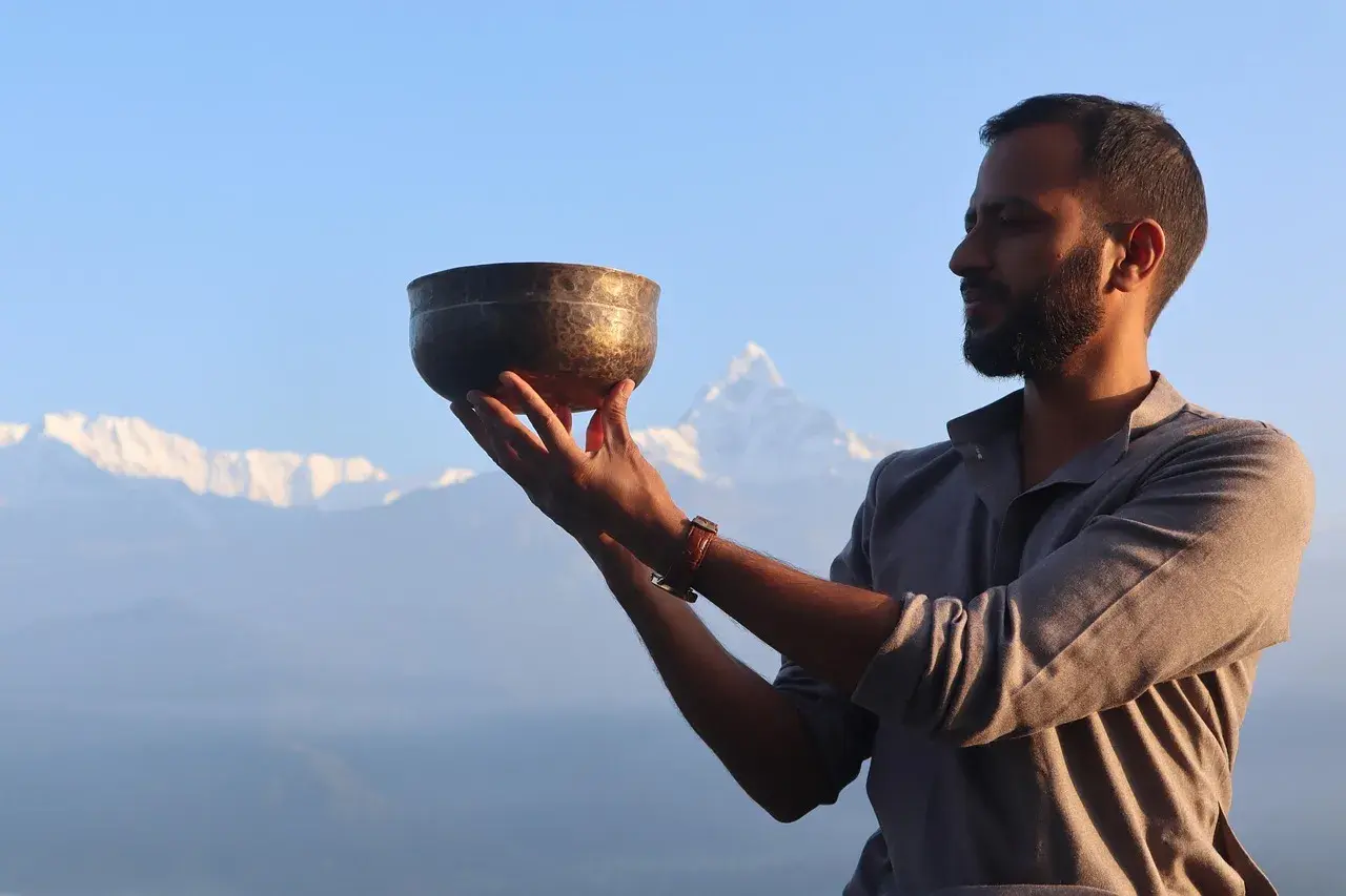 Yoga instructor holding a singing bowl during Poon Hill Yoga Trek in Nepal with Machhapuchhre Fishtail mountain in the background.