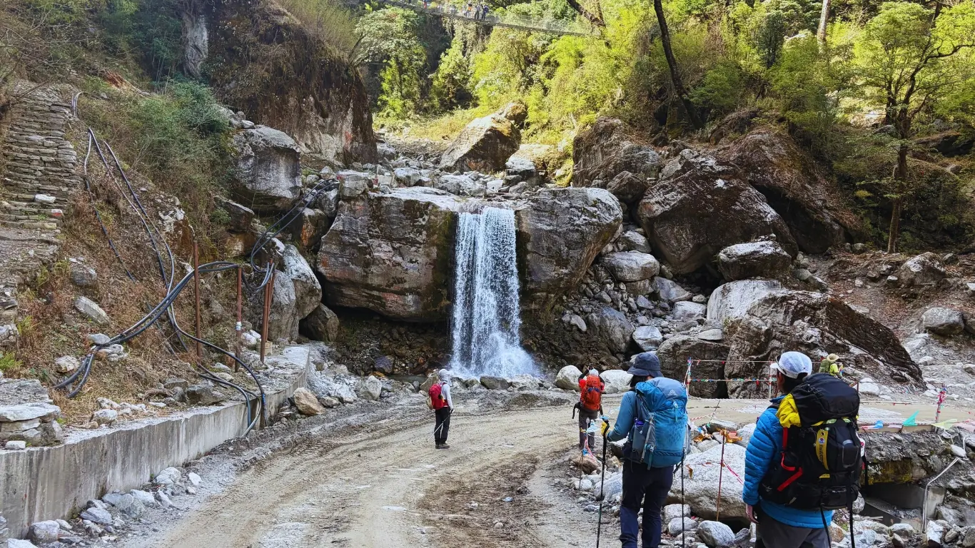 Trekkers crossing waterfall section on Nar Phu Valley Trek rugged mountain path