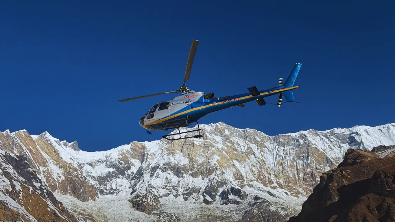 Helicopter flying near Annapurna Base Camp with Annapurna I peak towering behind, showcasing the majestic Himalayan landscape.