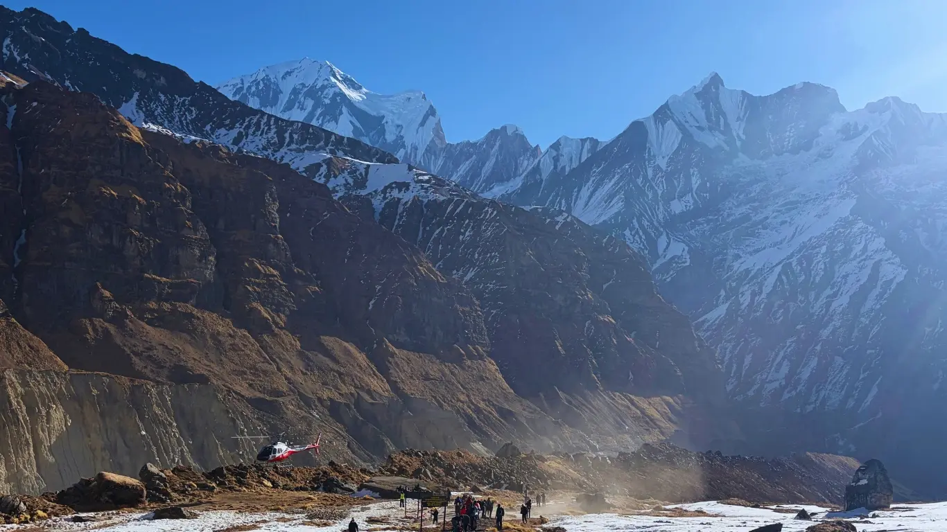 Helicopter taking off from Annapurna Base Camp area with GandharChuli peak in the background, flying over the Annapurna region.