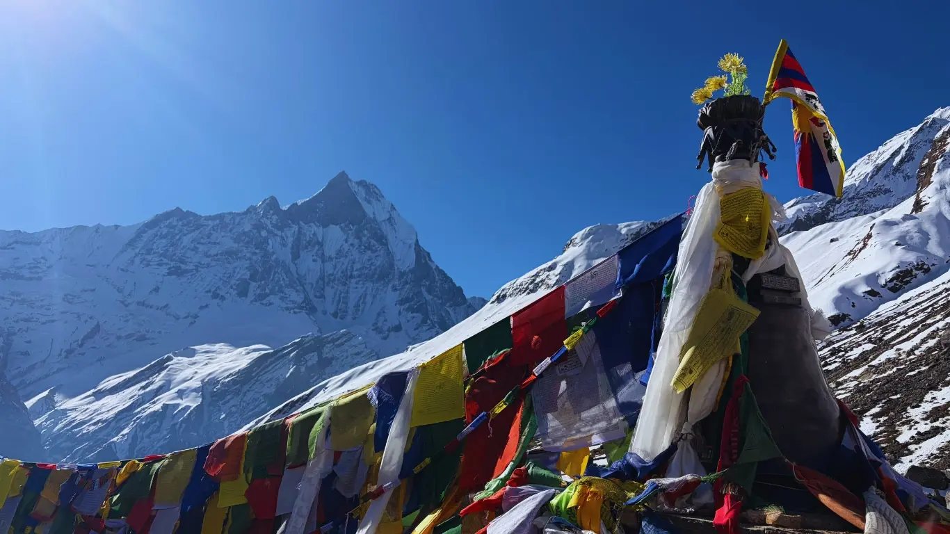 Colorful prayer flags at Annapurna Base Camp with Machapuchare (Fishtail Mountain) rising prominently in the background.
